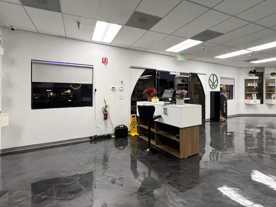 Cannabis dispensary checkout counter with glossy floor and display shelves