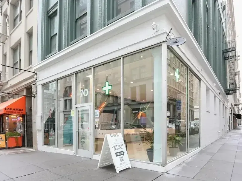 Corner storefront with glass windows and green cross sign